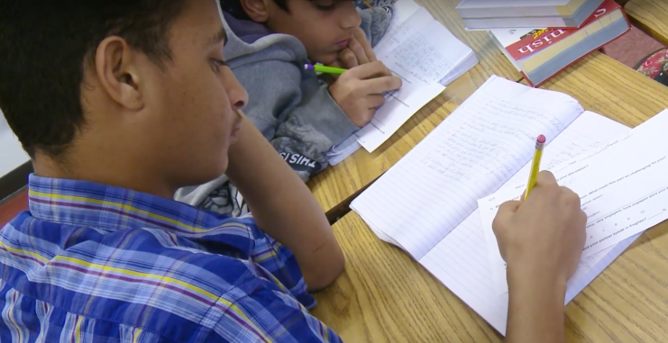 Two students writing in notebooks