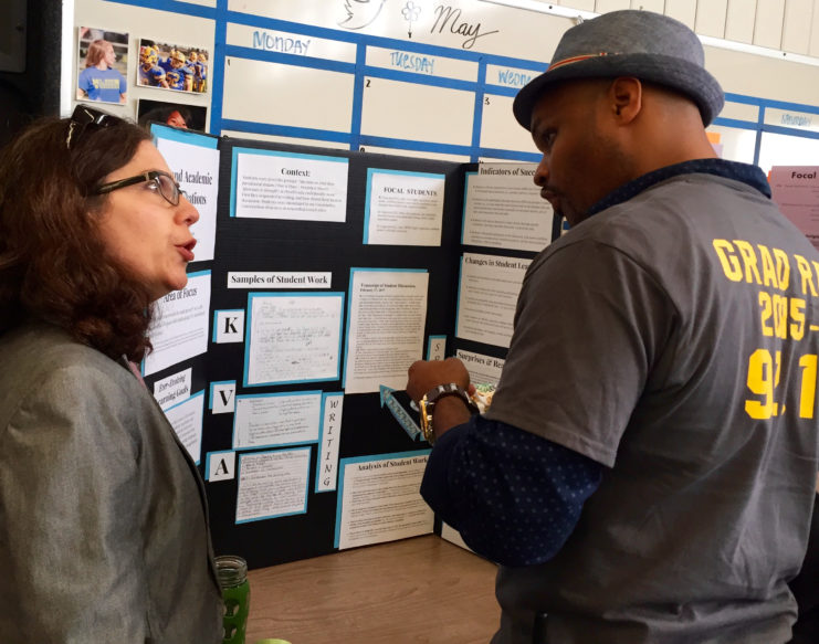 Two teachers talking about a poster