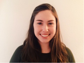 A young woman with pale skin and straight brown hair smiles into the camera