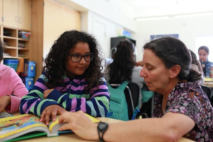 teacher and student engaged in a book